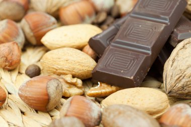 Bar of chocolate and nuts on a wicker mat