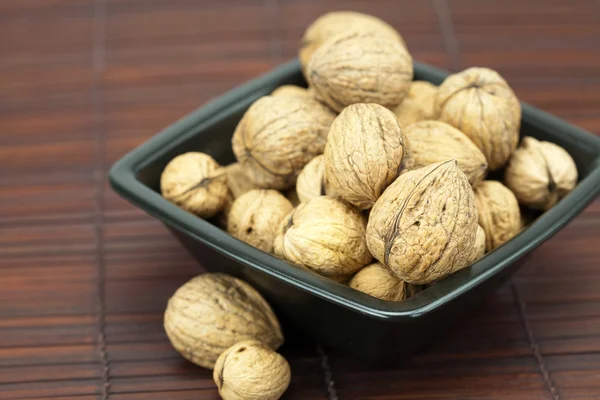 Walnuts in a bowl on a bamboo mat — Stockfoto