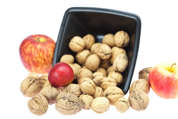 Valnötter i en skål och äpplen isolerad på vit — Stockfoto