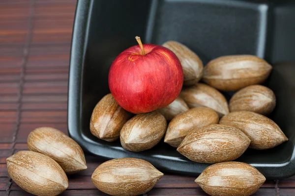 Pecans and apples in a bowl on a bamboo mat — Stock Photo, Image