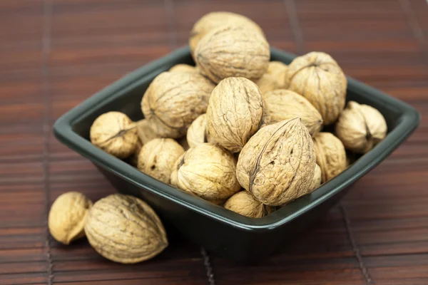 Walnuts in a bowl on a bamboo mat — Stok fotoğraf