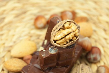 Bar of chocolate and nuts on a wicker mat