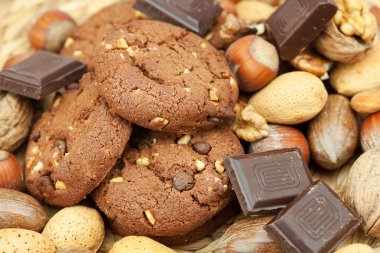 Oatmeal cookies, chocolate and nuts on a wicker mat clipart