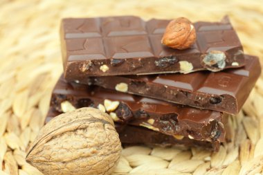 Bar of chocolate and nuts on a wicker mat