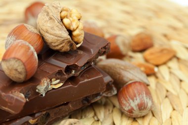 Bar of chocolate and nuts on a wicker mat