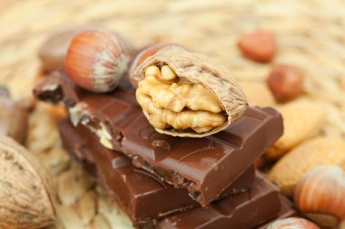 Bar of chocolate and nuts on a wicker mat