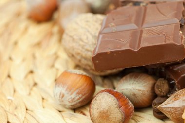 Bar of chocolate and nuts on a wicker mat