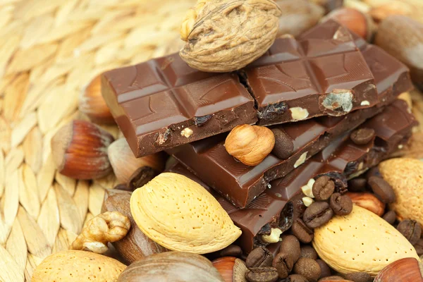 Bar of chocolate and nuts on a wicker mat — Stockfoto