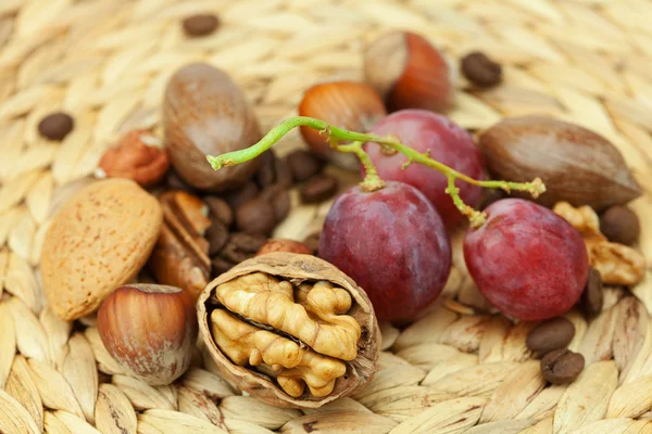 Nötter och druvor på en flätad matta — Stockfoto