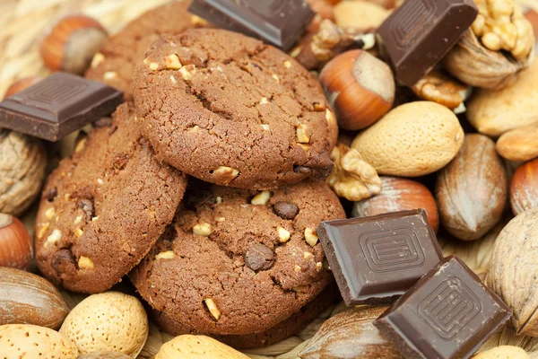 Oatmeal cookies, chocolate and nuts on a wicker mat — Stock Photo, Image