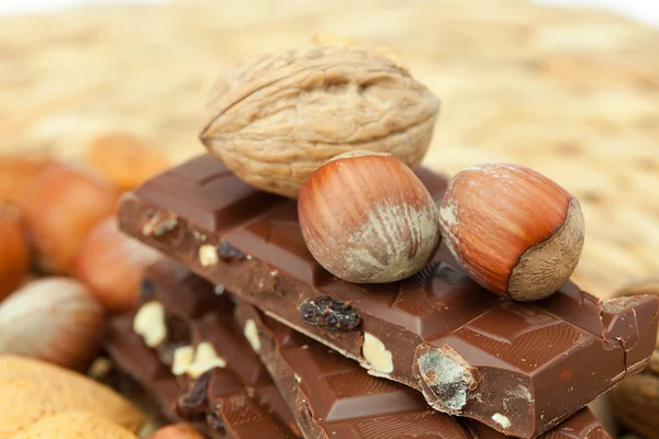 Bar of chocolate and nuts on a wicker mat — Stok fotoğraf
