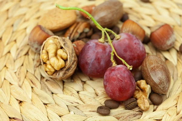 Орехи и виноград на плетеном коврике — стоковое фото