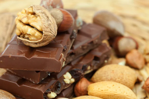 Bar of chocolate and nuts on a wicker mat — Stock Photo, Image