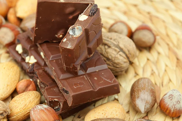 Tafel Schokolade und Nüsse auf einer Weidenmatte — Stockfoto
