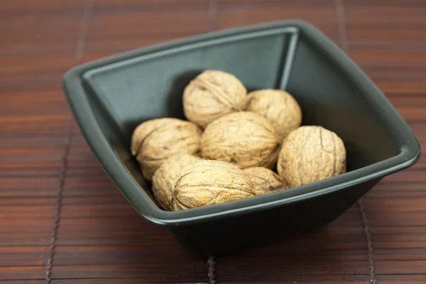 Walnuts in a bowl on a bamboo mat — Stock Photo, Image