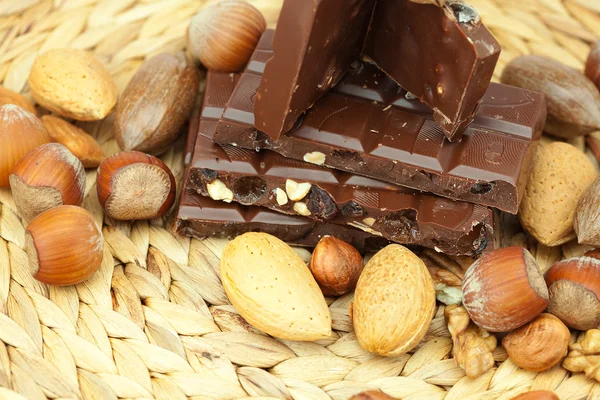 Bar of chocolate and nuts on a wicker mat — Stok fotoğraf