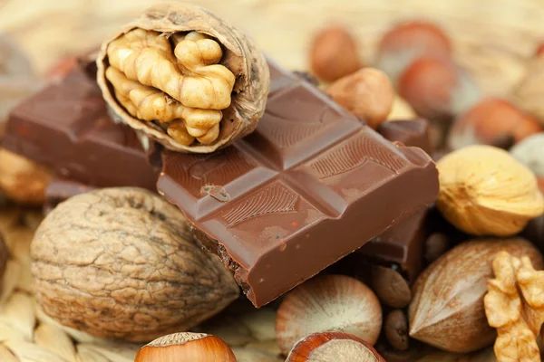Bar of chocolate and nuts on a wicker mat — Stock Photo, Image
