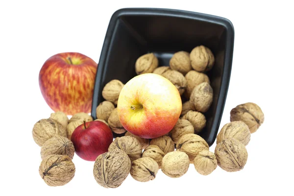 Valnötter i en skål och äpplen isolerad på vit — Stockfoto