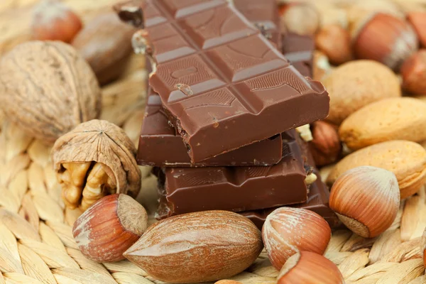 Tafel Schokolade und Nüsse auf einer Weidenmatte — Stockfoto