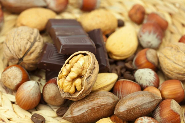 Bar of chocolate and nuts on a wicker mat — Stock Photo, Image