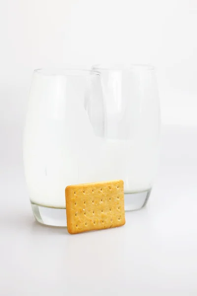 Dvě sklenice mléka a soubory cookie na šedém pozadí — Stock fotografie