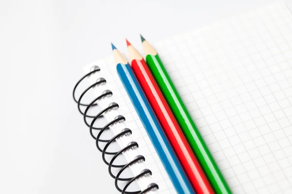 Lápices de colores y un cuaderno aislado en blanco — Foto de Stock