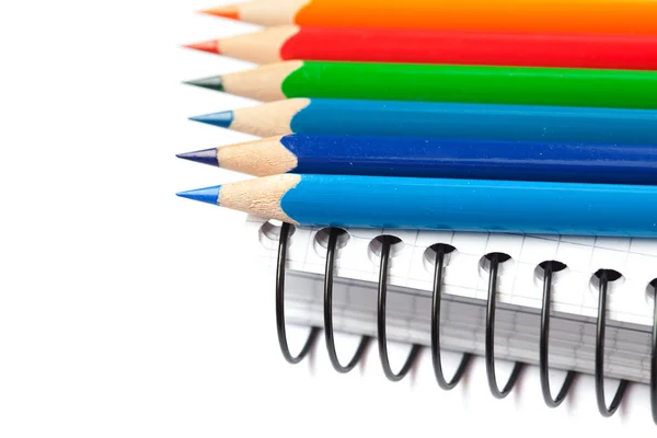 Lápices de colores y un cuaderno aislado en blanco — Foto de Stock