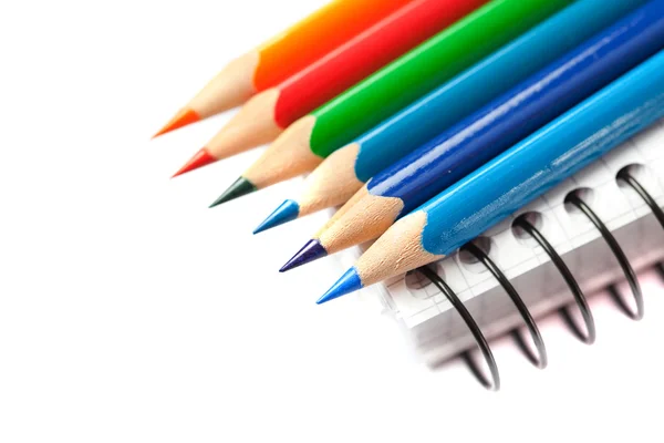 Χρωματιστά μολύβια και ένα σημειωματάριο που απομονώνονται σε λευκό — Φωτογραφία Αρχείου