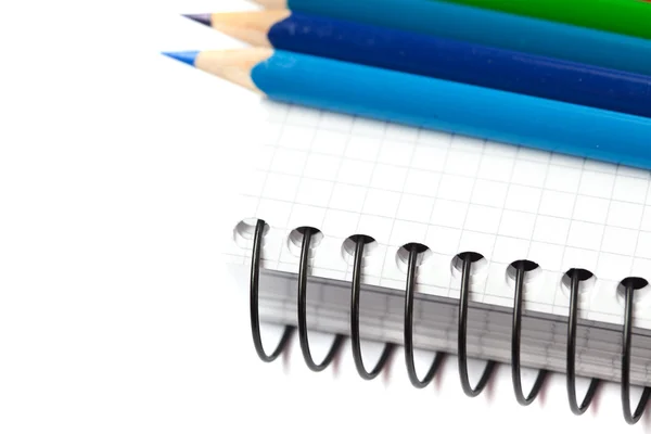 Kleurpotloden en een notebook geïsoleerd op wit — Stockfoto