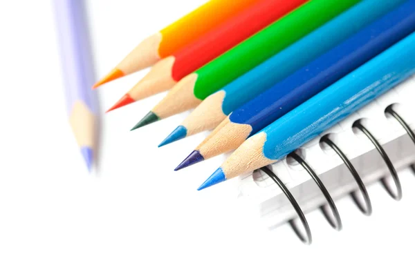 Crayons de couleur et un carnet isolé sur blanc — Photo