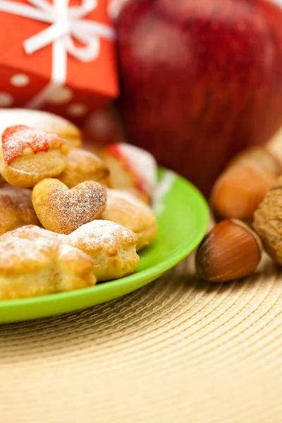 Plat, biscuits, noix, pomme, arcs, boîtes, cadeaux, boules de Noël — Photo