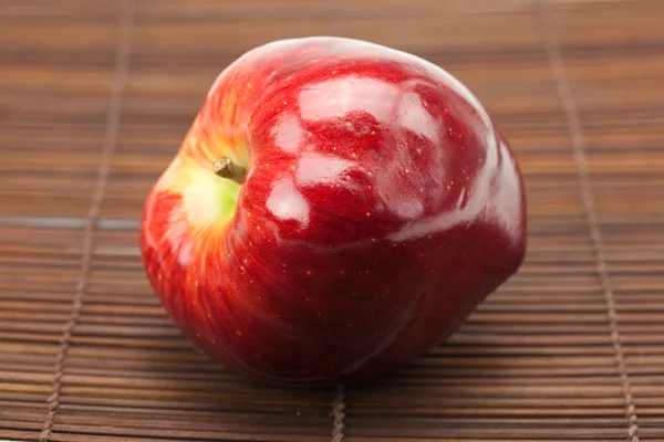 Красное яблоко на бамбуковом коврике — стоковое фото