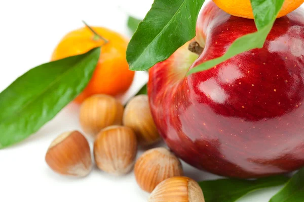 Красное яблоко, мандарин с зелеными листьями и орехами изолированы по whi — стоковое фото