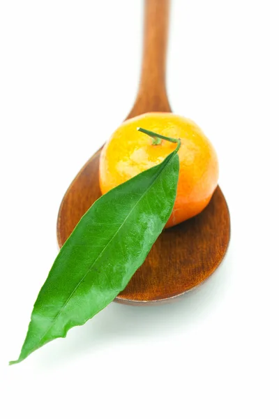 Mandarine mit grünen Blättern auf einem Holzlöffel isoliert auf weiß — Stockfoto