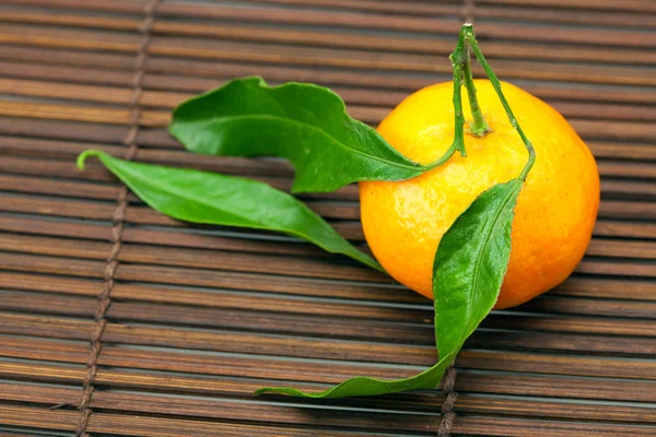 Mandarin with green leaves on a bamboo mat — Stock Photo, Image