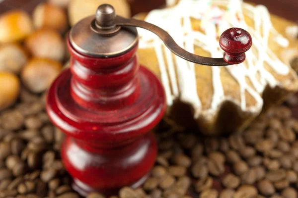 Mlýnek na kávu, dortík s poleva, oříšky a kávová zrna na b — Stock fotografie