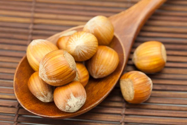 Hazelnuts on a wooden spoon on a bamboo mat Stock Photo