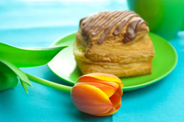 Cake met chocolade op de plaat, tulip en een kop op het weefsel — Stockfoto