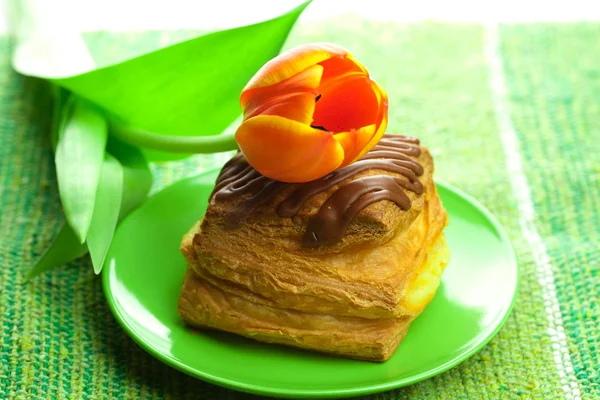 Kuchen mit Schokolade und Tulpen auf einem Teller auf dem Stoff — Stockfoto