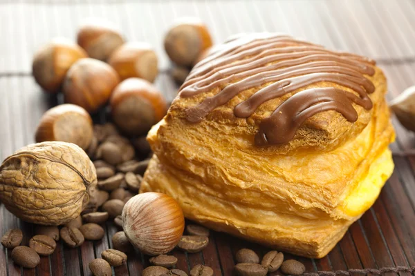 Dort s čokoládou, kávová zrna a ořechy, ležící na bambusové rohoži — Stock fotografie