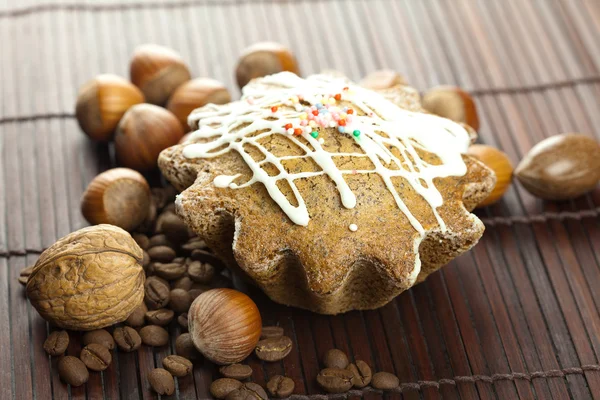 Cake with icing, coffee beans and nuts lying on a bamboo mat — Stock Photo, Image