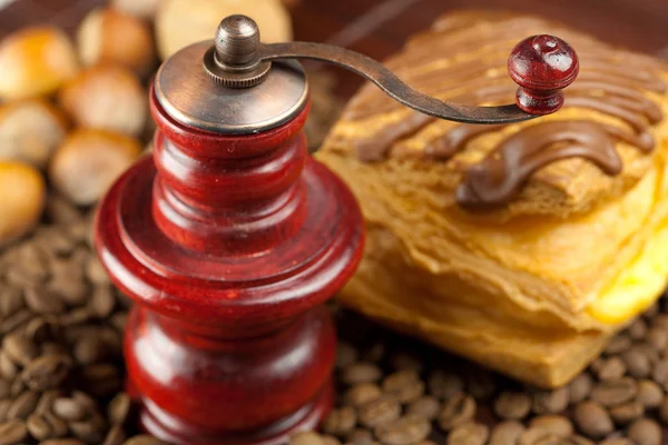 Coffee grinder, cake with chocolate, nuts and coffee beans on a — Stock Photo, Image