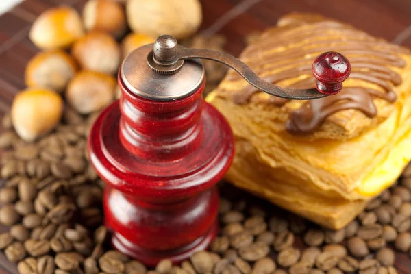Coffee grinder, cake with chocolate, nuts and coffee beans on a — Stock Photo, Image