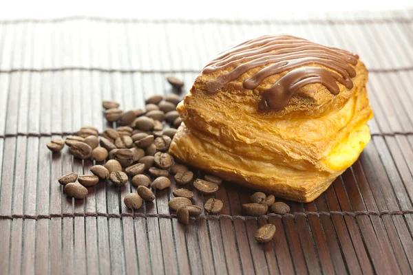 Kuchen mit Schokolade und Kaffeebohnen auf einer Bambusmatte liegend — Stockfoto