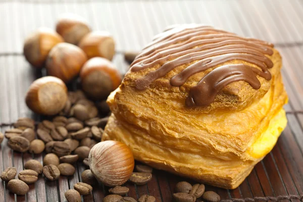 Cake with chocolate, coffee beans and nuts lying on a bamboo mat — Stock Photo, Image
