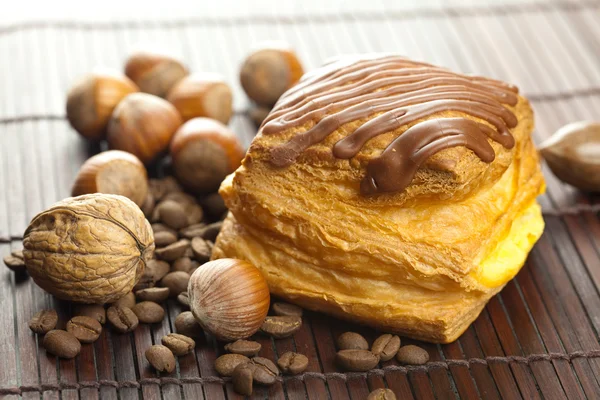 Dort s čokoládou, kávová zrna a ořechy, ležící na bambusové rohoži — Stock fotografie