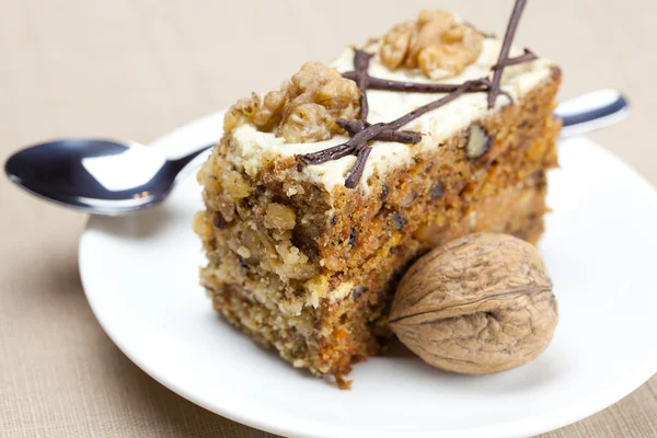 Pedaço de bolo com nozes e colher deitado em um prato — Fotografia de Stock