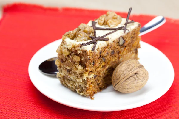 Pedazo de pastel con nueces y cuchara acostado en un plato —  Fotos de Stock