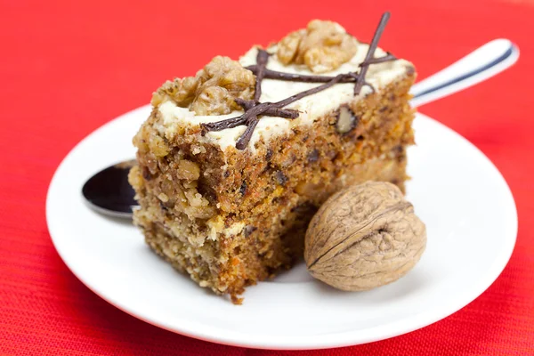 Лежит на тарелке кусок торта с орехами и ложкой — стоковое фото