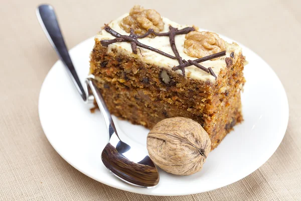 Лежит на тарелке кусок торта с орехами и ложкой — стоковое фото